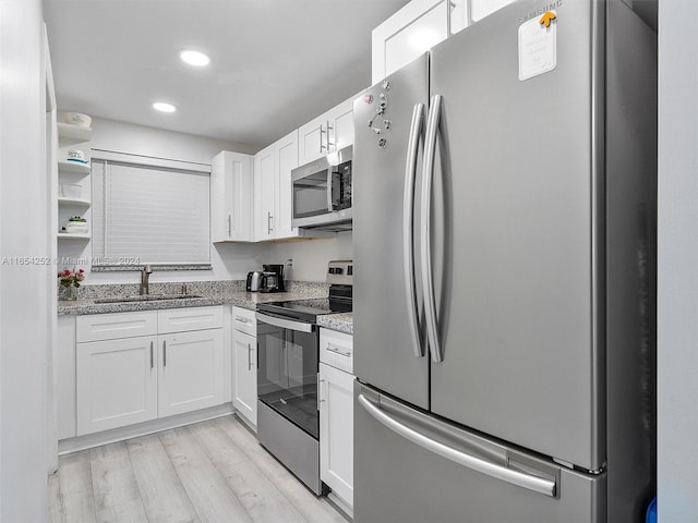 kitchen featuring light stone counters, sink, appliances with stainless steel finishes, white cabinets, and light hardwood / wood-style floors