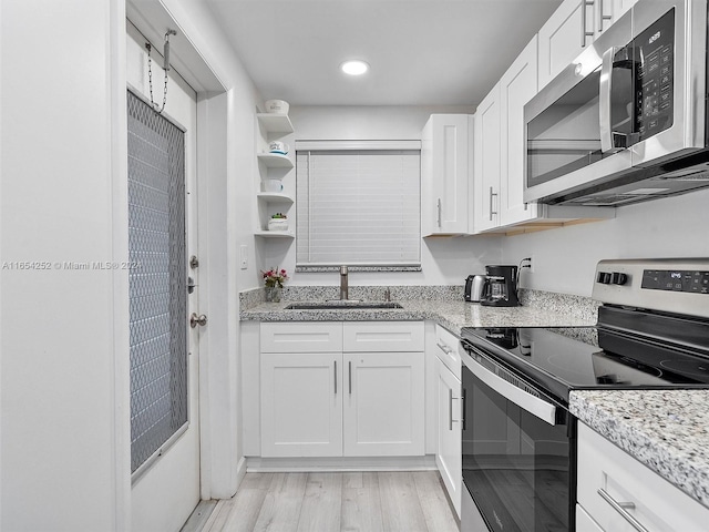 kitchen featuring appliances with stainless steel finishes, light hardwood / wood-style floors, white cabinetry, and sink