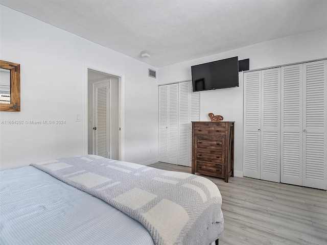 bedroom featuring multiple closets and light hardwood / wood-style floors