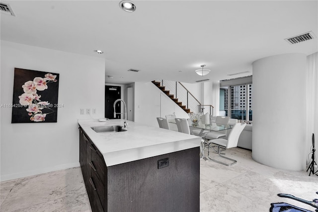 kitchen featuring kitchen peninsula, dark brown cabinetry, and sink