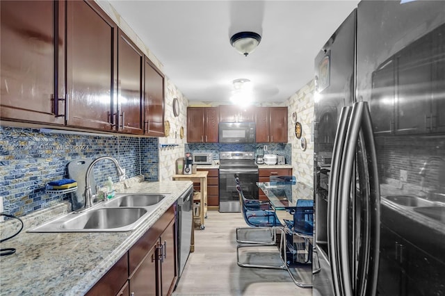 kitchen with sink, light stone countertops, decorative backsplash, appliances with stainless steel finishes, and light hardwood / wood-style floors