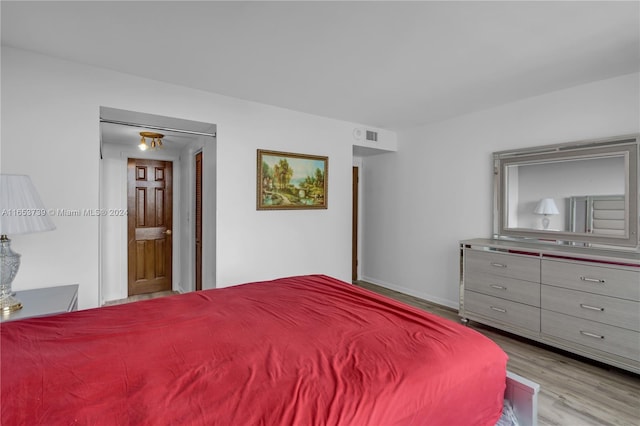 bedroom with ensuite bathroom and light hardwood / wood-style floors