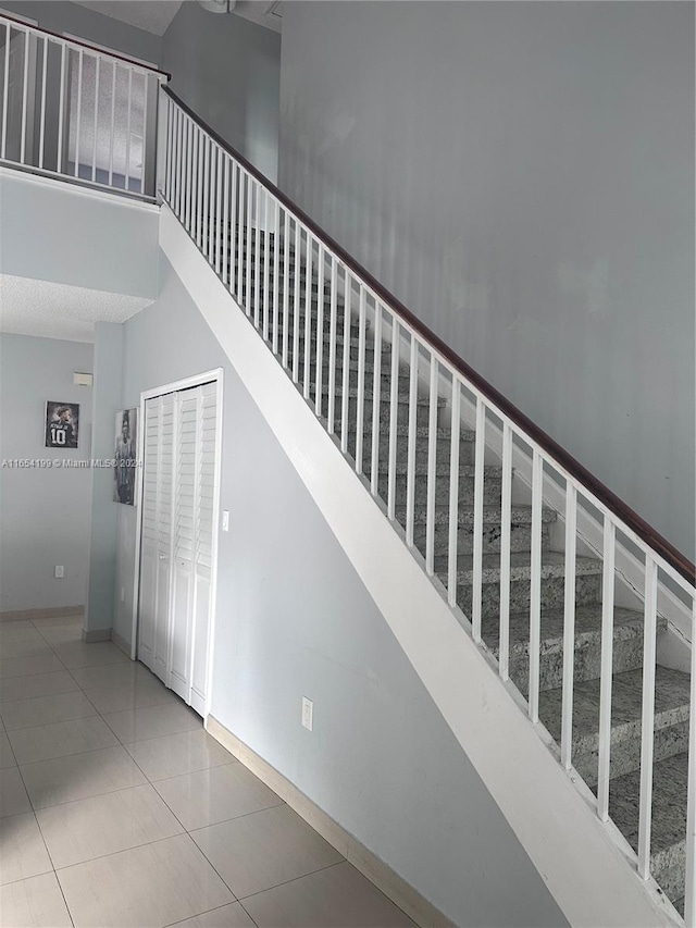 stairs featuring tile patterned flooring and a high ceiling