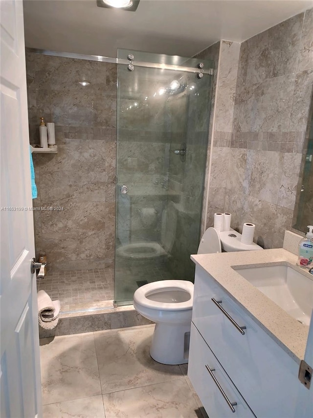 bathroom featuring vanity, toilet, tile walls, and a shower with shower door