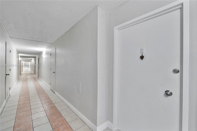 hall featuring light tile patterned floors and a textured ceiling