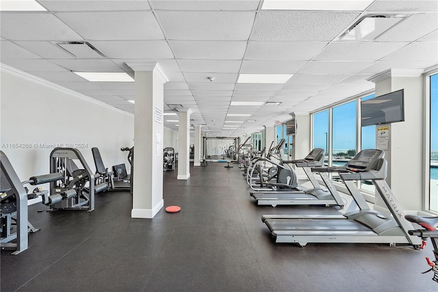 workout area with floor to ceiling windows, ornate columns, ornamental molding, and a drop ceiling