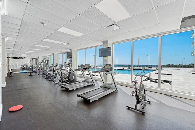 exercise room with a wall of windows and a drop ceiling