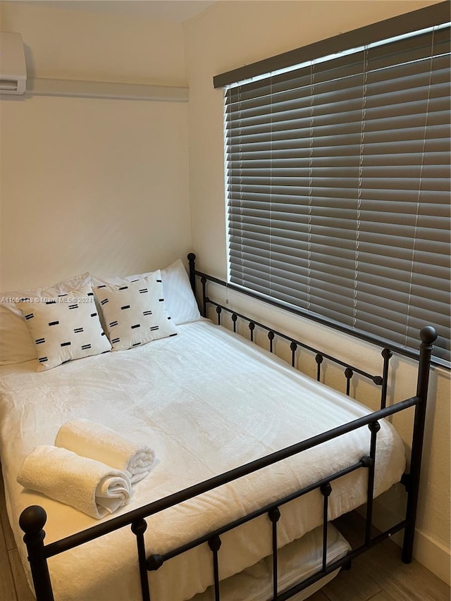 bedroom with hardwood / wood-style floors and an AC wall unit