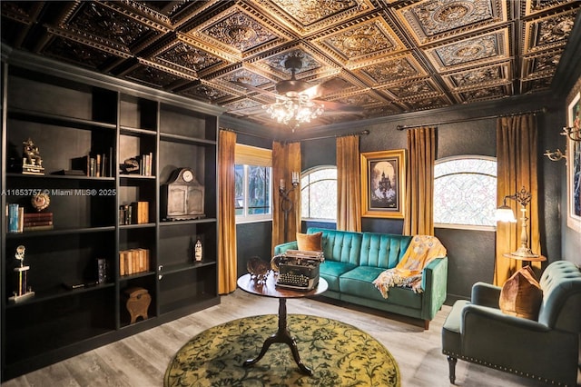 sitting room with wood-type flooring, built in features, and ceiling fan