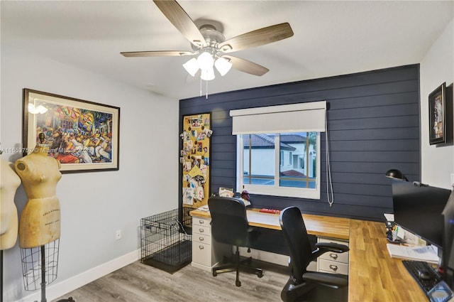 office space featuring ceiling fan, wooden walls, and light wood-type flooring