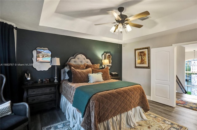 bedroom featuring dark wood-type flooring, ceiling fan, and a tray ceiling