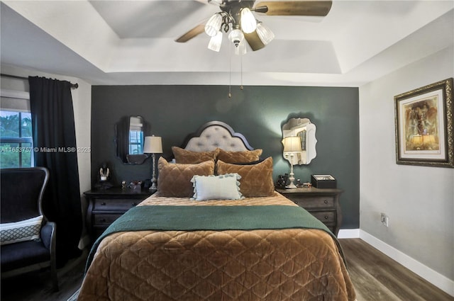 bedroom featuring a raised ceiling, wood-type flooring, and ceiling fan