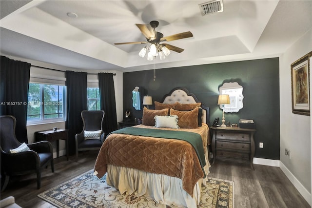 bedroom featuring ceiling fan, a tray ceiling, and dark hardwood / wood-style flooring