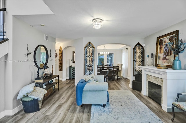 living room with an inviting chandelier, hardwood / wood-style floors, and a fireplace