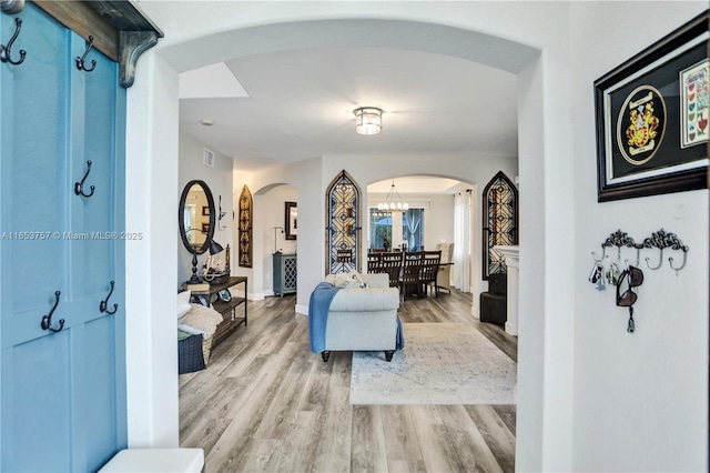 corridor featuring light hardwood / wood-style flooring and a chandelier