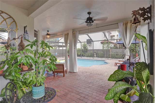 view of swimming pool featuring a patio, ceiling fan, and glass enclosure