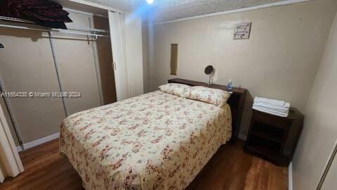 bedroom with dark wood-type flooring and a closet