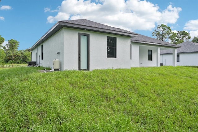 rear view of property featuring central AC unit and a lawn