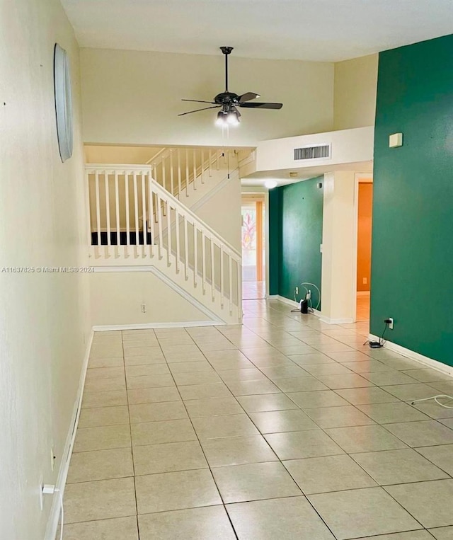 empty room with ceiling fan, high vaulted ceiling, and light tile patterned floors