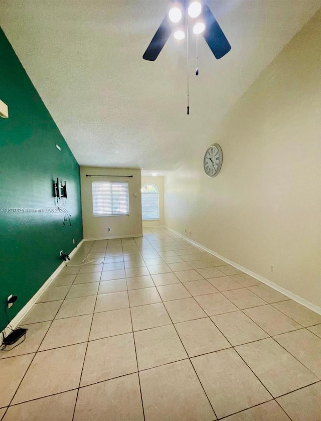 unfurnished room with light tile patterned floors, a textured ceiling, lofted ceiling, and ceiling fan