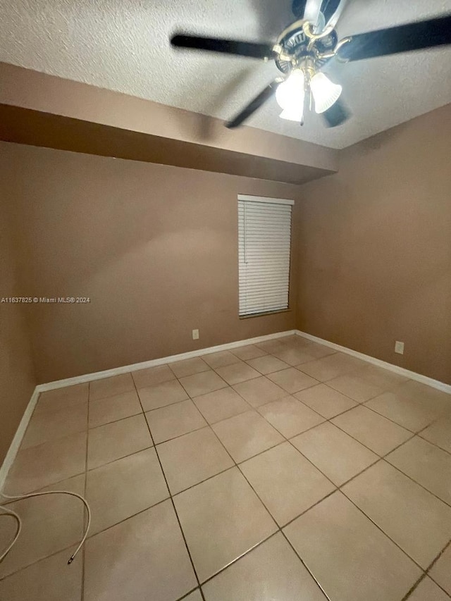 tiled spare room with a textured ceiling and ceiling fan