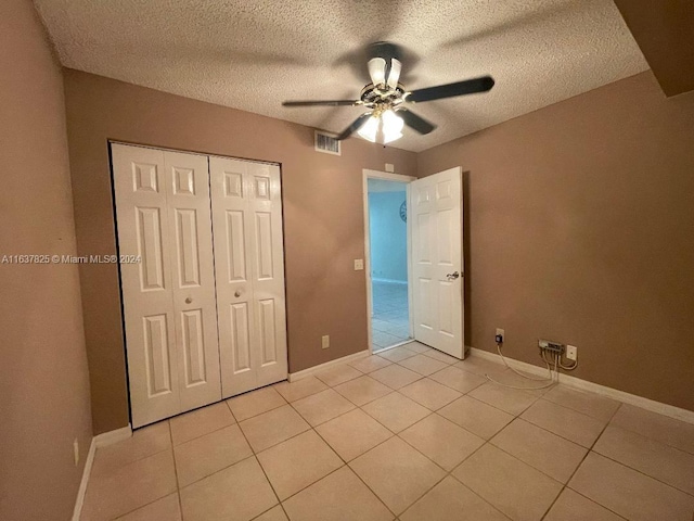 unfurnished bedroom with a closet, a textured ceiling, light tile patterned floors, and ceiling fan