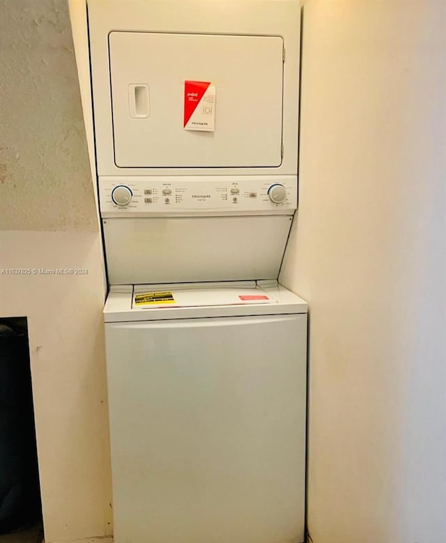 clothes washing area with stacked washing maching and dryer