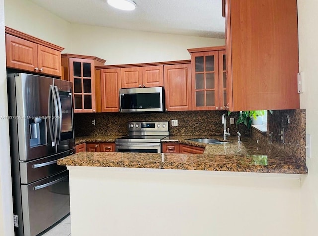 kitchen with kitchen peninsula, backsplash, appliances with stainless steel finishes, vaulted ceiling, and sink