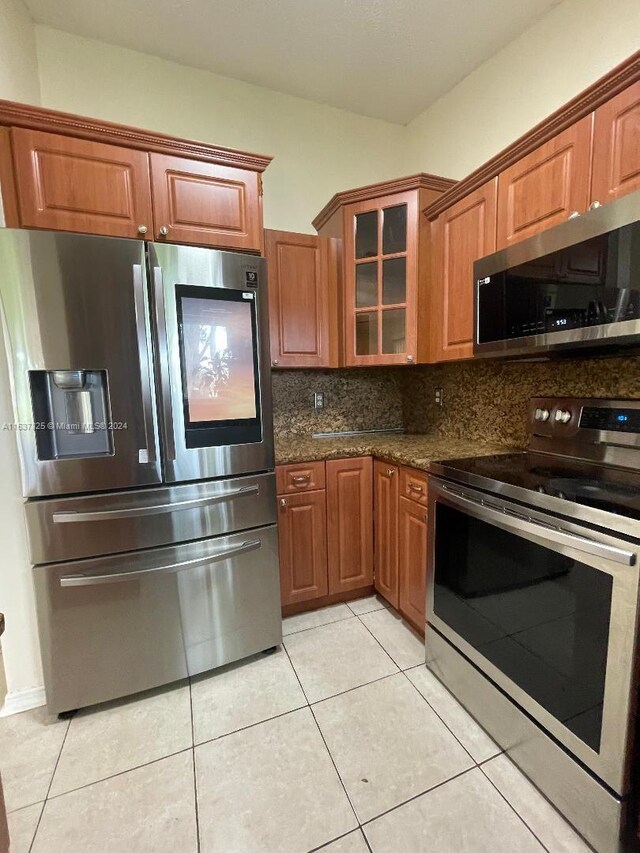 kitchen featuring decorative backsplash, appliances with stainless steel finishes, dark stone counters, and light tile patterned floors