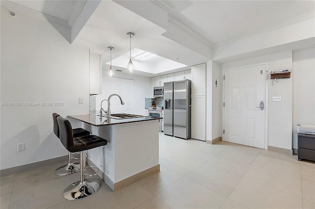 kitchen featuring appliances with stainless steel finishes, a sink, decorative backsplash, and ornamental molding