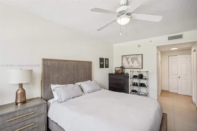 bedroom featuring visible vents, ceiling fan, a textured ceiling, and light tile patterned floors