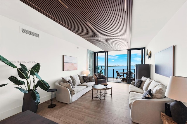 living room featuring a water view, a wall of windows, and hardwood / wood-style flooring