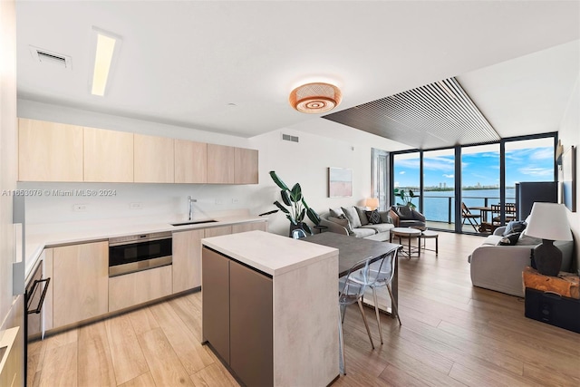 kitchen with a kitchen island, oven, light hardwood / wood-style flooring, sink, and a water view