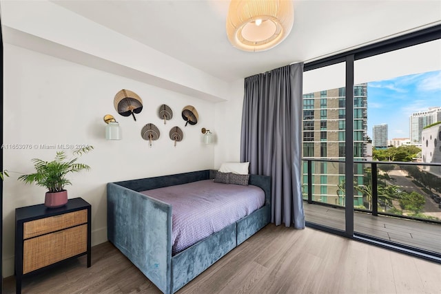 bedroom featuring a city view, wood finished floors, and expansive windows