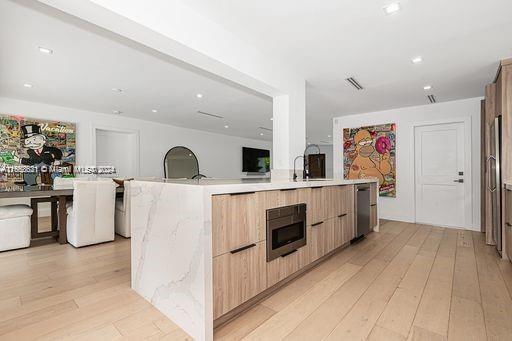 kitchen featuring a center island with sink, light hardwood / wood-style flooring, stainless steel appliances, and light brown cabinets