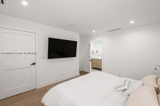 bedroom with connected bathroom and light wood-type flooring