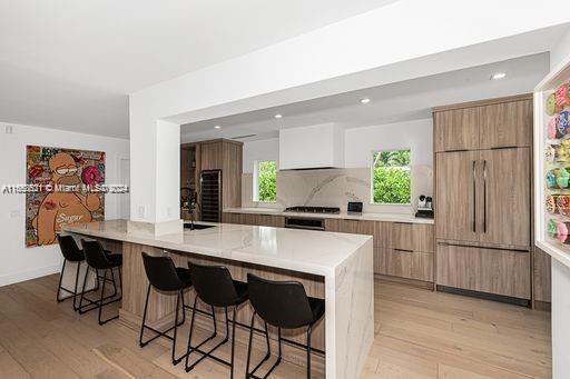5231 SW 65th Ave, South Miami, FL 33155 - kitchen featuring modern cabinets, a kitchen breakfast bar, light wood-style flooring, light countertops, and recessed lighting