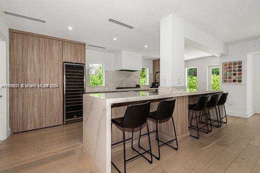 5231 SW 65th Ave, South Miami, FL 33155 - kitchen featuring wine cooler, modern cabinets, light wood-style flooring, a breakfast bar area, and recessed lighting