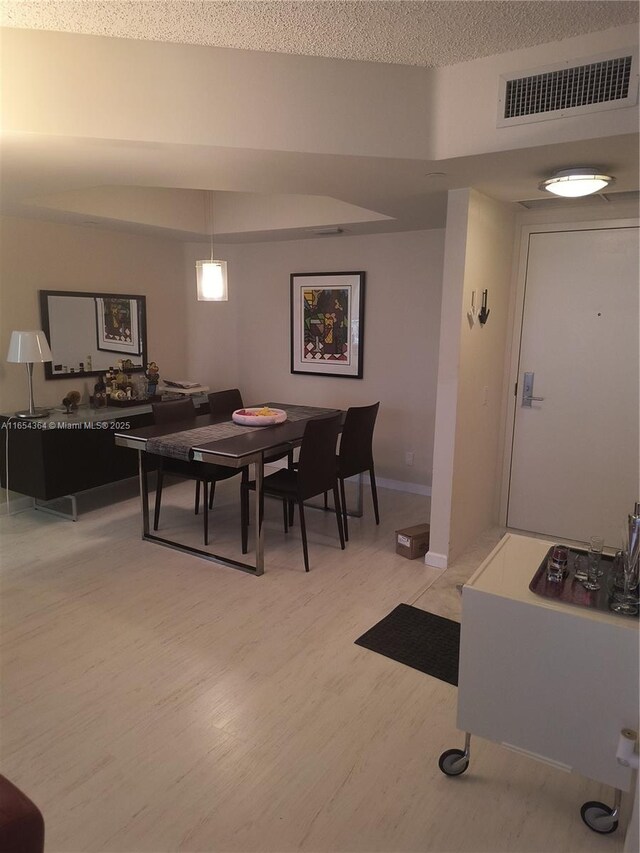 dining space featuring a textured ceiling and light hardwood / wood-style flooring