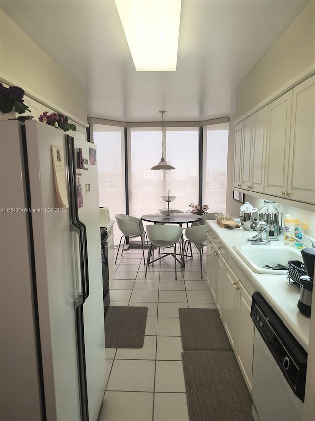 kitchen featuring light tile patterned floors, white appliances, a sink, light countertops, and hanging light fixtures