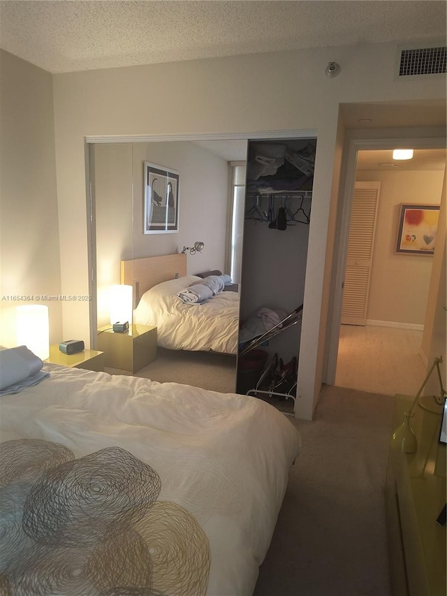 carpeted bedroom featuring a textured ceiling, visible vents, and a closet