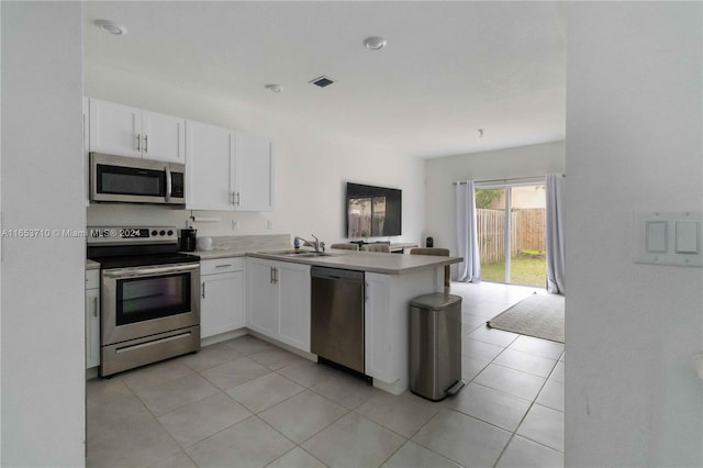 kitchen with stainless steel appliances, sink, kitchen peninsula, and white cabinetry