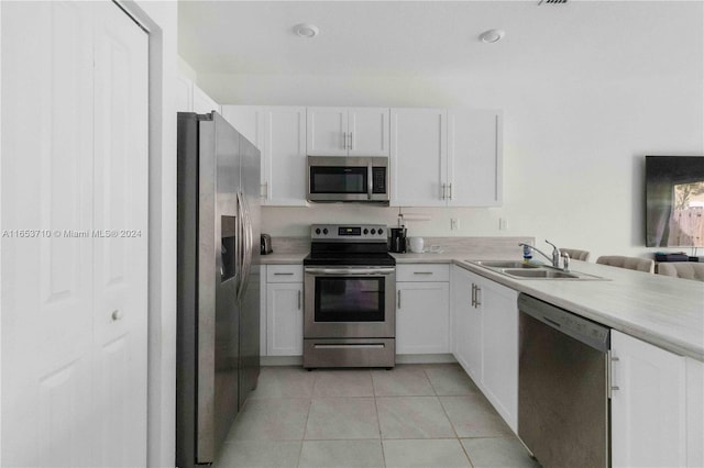 kitchen featuring appliances with stainless steel finishes, light tile patterned floors, sink, and white cabinets