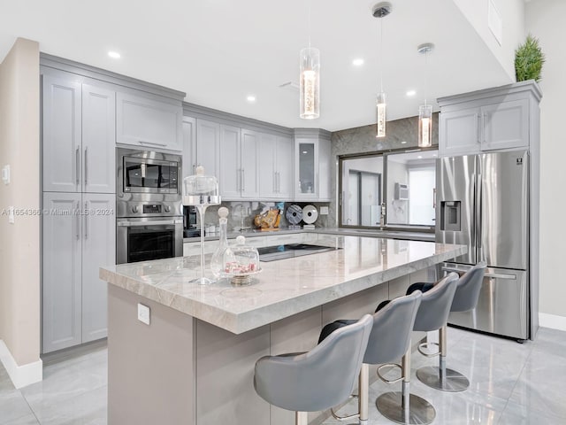 kitchen featuring a kitchen island, stainless steel appliances, light stone countertops, and a breakfast bar