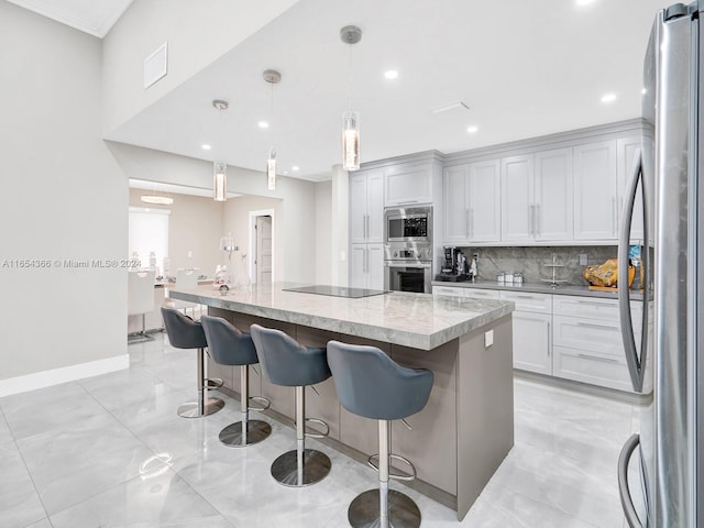 kitchen with light stone countertops, a center island with sink, a kitchen bar, hanging light fixtures, and stainless steel appliances