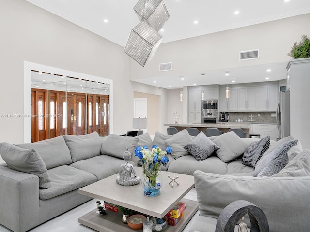 living room with a towering ceiling and ornamental molding