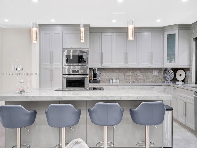 kitchen with light stone counters, decorative backsplash, and a breakfast bar