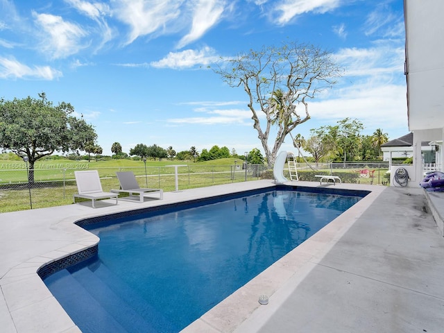 view of swimming pool featuring a lawn, a water slide, and a patio