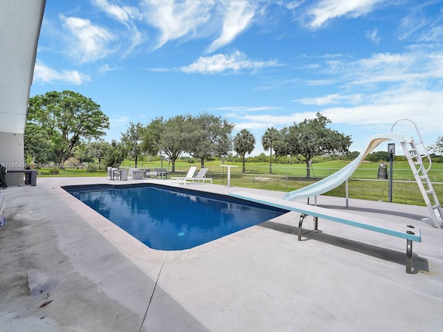 view of pool with a lawn, a water slide, and a patio area