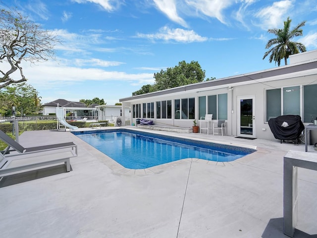 view of swimming pool featuring area for grilling, a water slide, and a patio